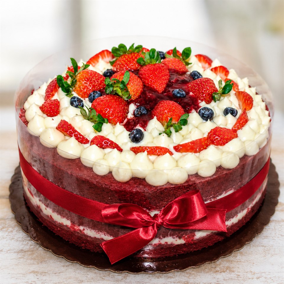 Bolo decorado com frutas vermelhas e laço vermelho
